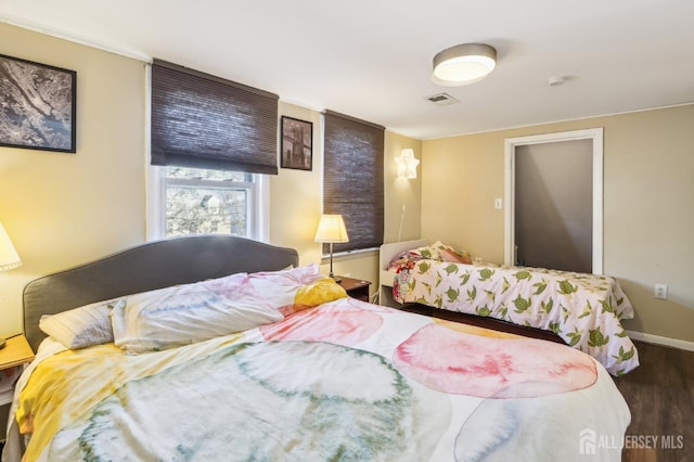 bedroom with wood finished floors, visible vents, and baseboards