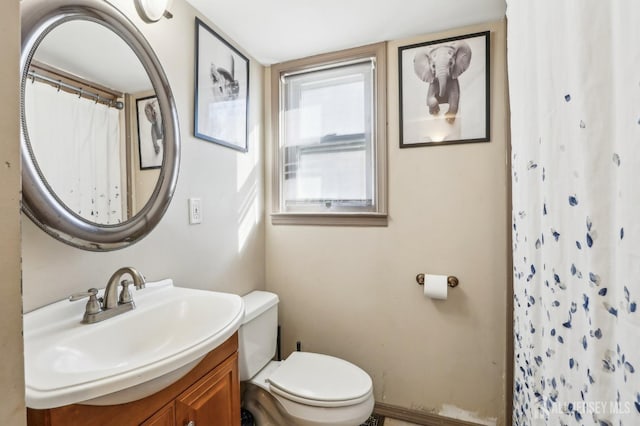 bathroom featuring a shower with shower curtain, toilet, and vanity