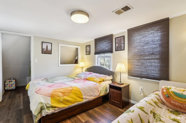 bedroom with dark wood-style floors, visible vents, and baseboards