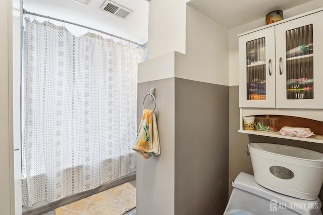 full bathroom featuring visible vents, toilet, and a shower with shower curtain