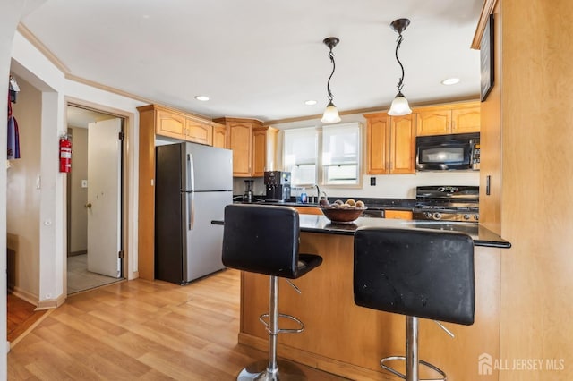 kitchen with dark countertops, freestanding refrigerator, a breakfast bar area, black microwave, and stove