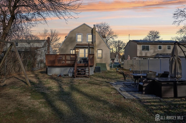 rear view of house featuring central air condition unit, a gambrel roof, a lawn, a deck, and fence