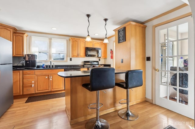 kitchen with stove, light wood finished floors, freestanding refrigerator, and black microwave