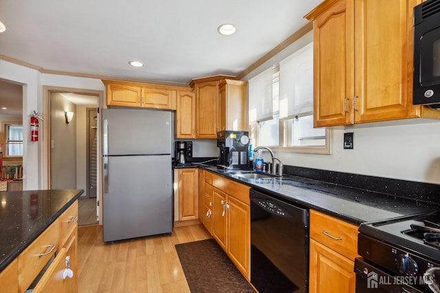 kitchen featuring black appliances, a sink, dark stone countertops, light wood-style floors, and crown molding