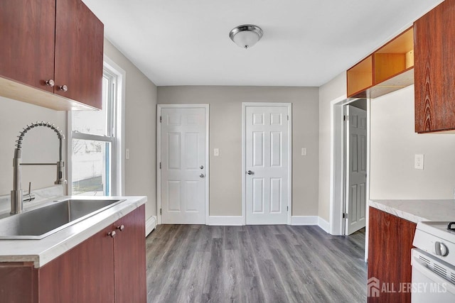 kitchen featuring white range, light countertops, a sink, wood finished floors, and baseboards