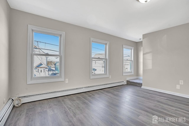 spare room featuring baseboards, baseboard heating, and wood finished floors