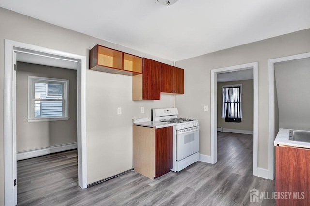 kitchen with white range with gas cooktop, baseboards, wood finished floors, baseboard heating, and light countertops