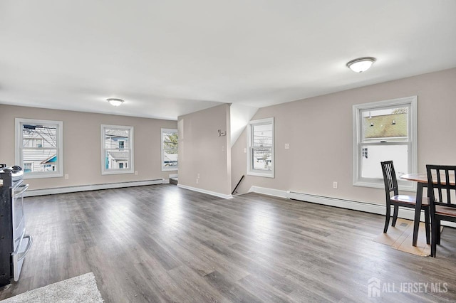 interior space with plenty of natural light, baseboard heating, and wood finished floors