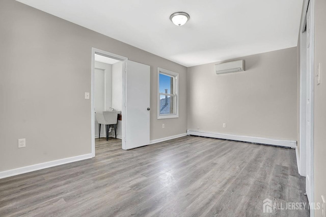 interior space featuring baseboards, a wall unit AC, a baseboard radiator, wood finished floors, and a sink