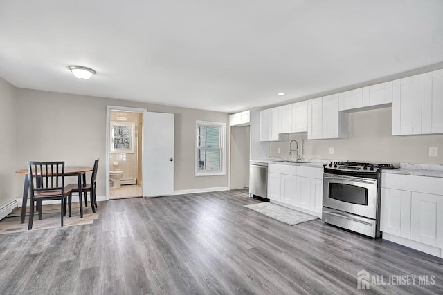 kitchen featuring stainless steel appliances, white cabinets, a sink, and wood finished floors