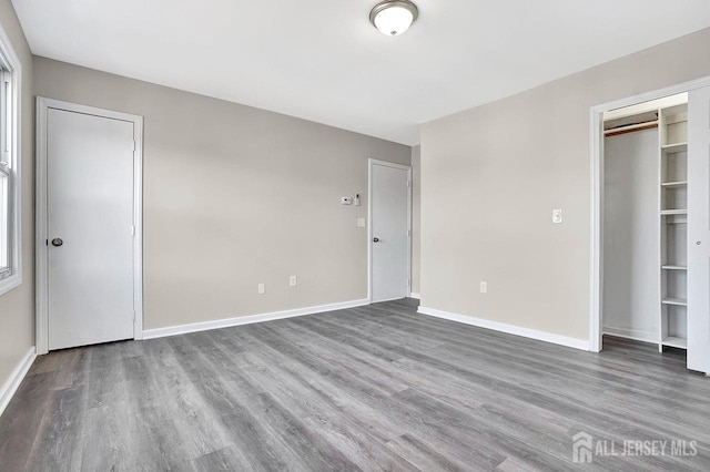 unfurnished bedroom with a closet, baseboards, and wood finished floors