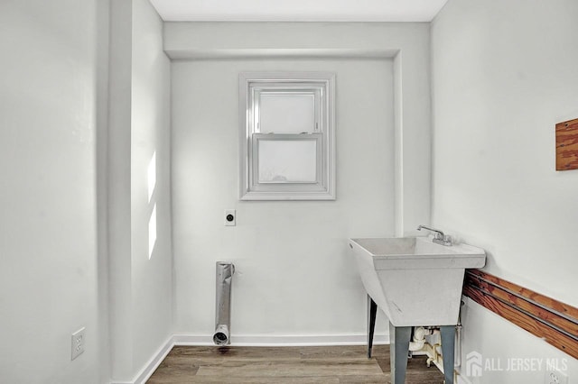 laundry area featuring laundry area, wood finished floors, electric dryer hookup, and baseboards