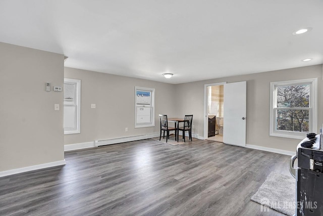 living area featuring baseboards, baseboard heating, and wood finished floors