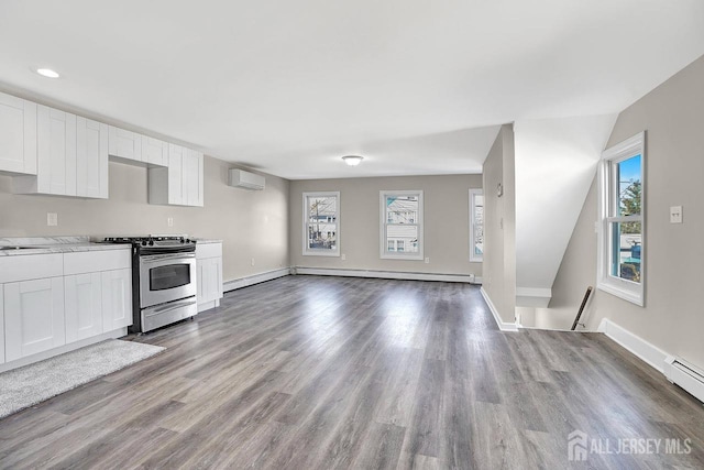 kitchen with a wall unit AC, white cabinets, light wood-style floors, baseboard heating, and stainless steel range with gas cooktop