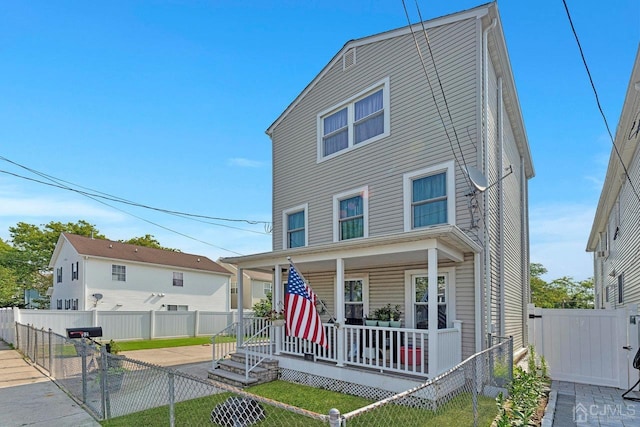 view of front of property featuring a porch, a front lawn, fence private yard, and a gate