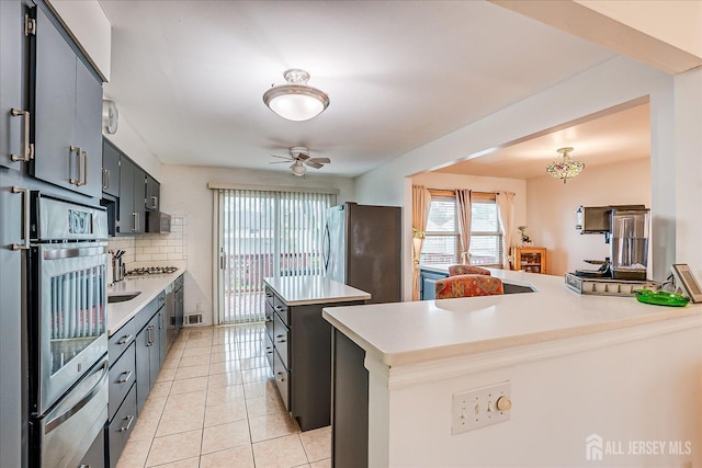 115 Broadway Ave, Colonia, NJ 07067 - kitchen with stainless steel appliances, tasteful backsplash, a peninsula, light countertops, and light tile patterned floors