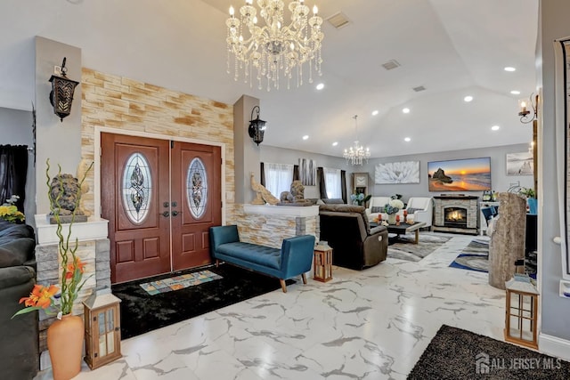 foyer entrance featuring marble finish floor, recessed lighting, an inviting chandelier, vaulted ceiling, and a lit fireplace