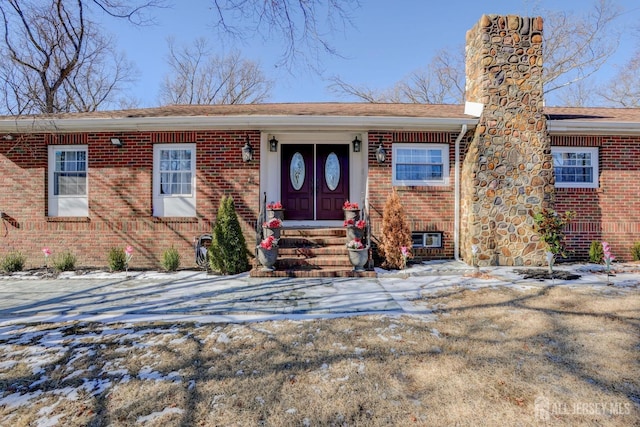 single story home featuring brick siding and a chimney