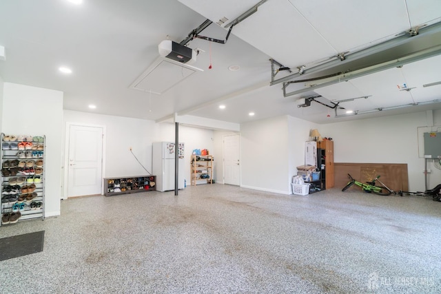 garage with freestanding refrigerator, a garage door opener, and recessed lighting
