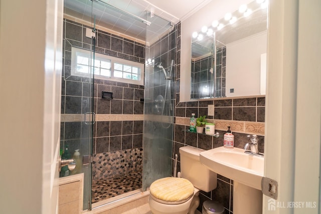 bathroom with tile walls, a shower stall, toilet, and crown molding