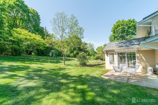 view of green lawn with a patio