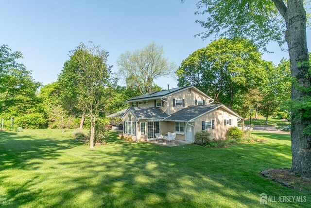 view of property exterior featuring a patio area, roof mounted solar panels, a lawn, and stucco siding