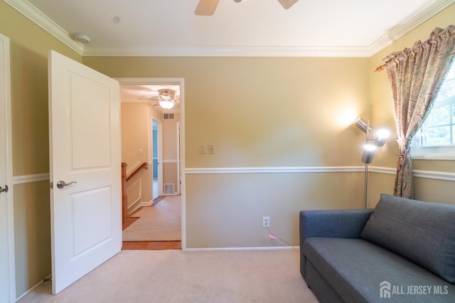 living area with a ceiling fan, ornamental molding, and light carpet