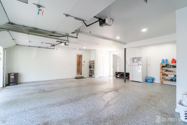garage featuring freestanding refrigerator, a garage door opener, and recessed lighting