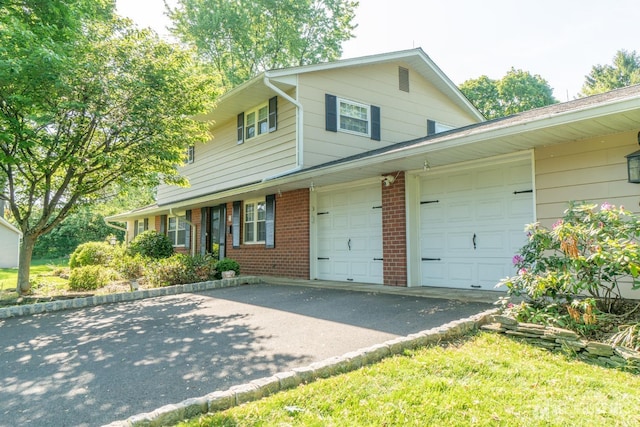traditional-style home featuring asphalt driveway, a garage, and brick siding