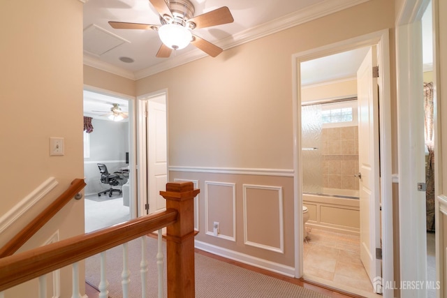 hallway featuring ornamental molding, an upstairs landing, a wainscoted wall, and a decorative wall