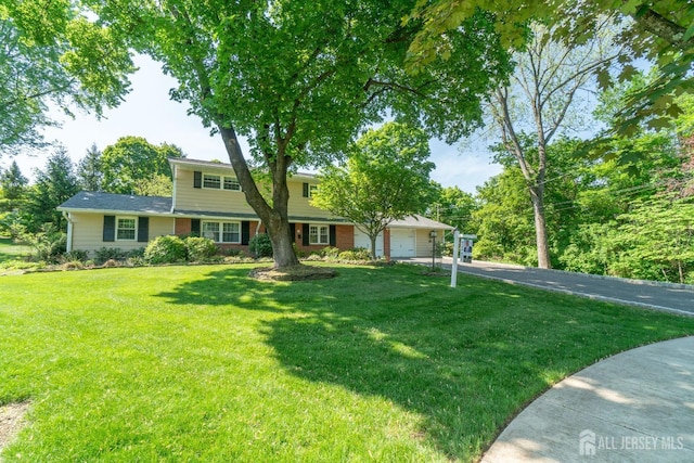 view of front facade with driveway, a garage, a front lawn, and brick siding