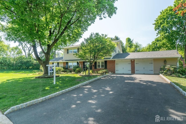 view of front of house with an attached garage, a front lawn, asphalt driveway, and brick siding