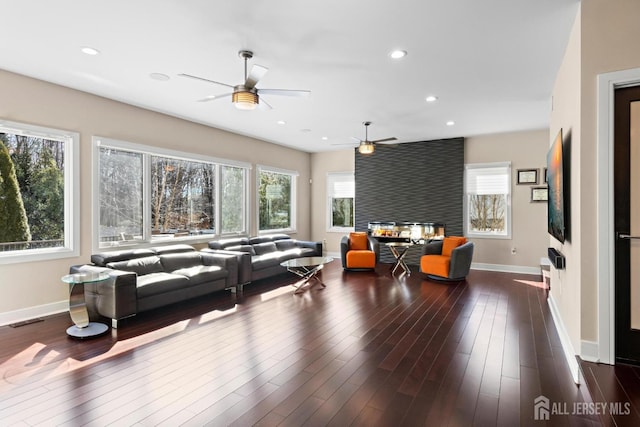 living area featuring dark wood-style floors, recessed lighting, a multi sided fireplace, and a healthy amount of sunlight