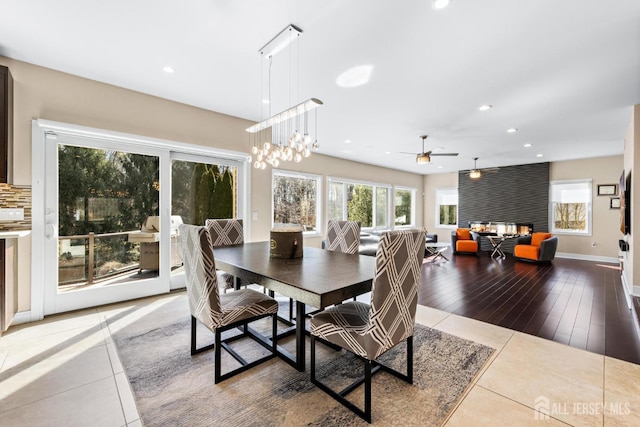 dining space with a wealth of natural light, tile patterned flooring, a multi sided fireplace, and recessed lighting