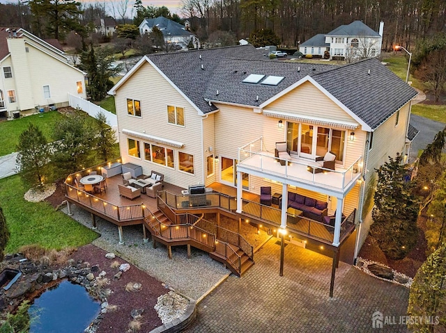 rear view of house with a shingled roof, outdoor lounge area, fence, stairway, and a wooden deck