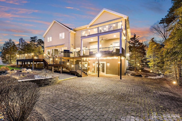 rear view of house with ceiling fan, a balcony, and stairs