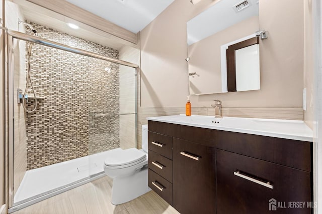 bathroom featuring toilet, a shower stall, visible vents, and vanity