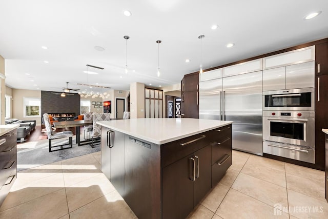 kitchen featuring a kitchen island, open floor plan, hanging light fixtures, light countertops, and a warming drawer