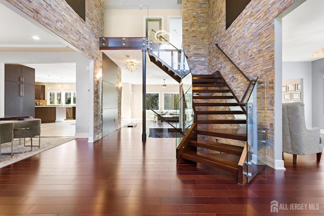 staircase with a high ceiling, baseboards, and wood finished floors