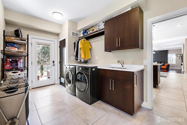 laundry room with light tile patterned flooring, a sink, visible vents, baseboards, and independent washer and dryer