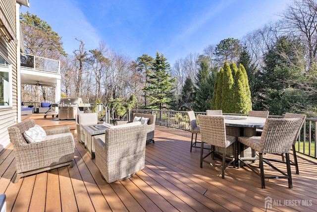 wooden deck with outdoor dining space, area for grilling, and an outdoor living space with a fire pit