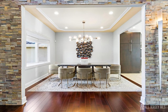 dining area featuring dark wood-style floors, baseboards, ornamental molding, and an inviting chandelier