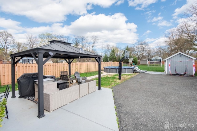 view of patio / terrace with a shed, a gazebo, a fenced backyard, an outdoor hangout area, and a fenced in pool
