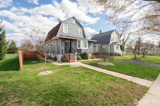 dutch colonial featuring a gambrel roof, a front yard, and fence