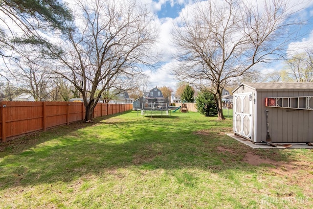 view of yard featuring a storage shed, a fenced backyard, an outdoor structure, and a trampoline