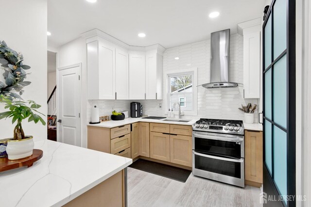 kitchen featuring a sink, wall chimney range hood, decorative backsplash, and double oven range