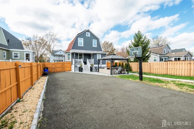 back of house featuring a gazebo, a patio area, a gambrel roof, and a fenced backyard