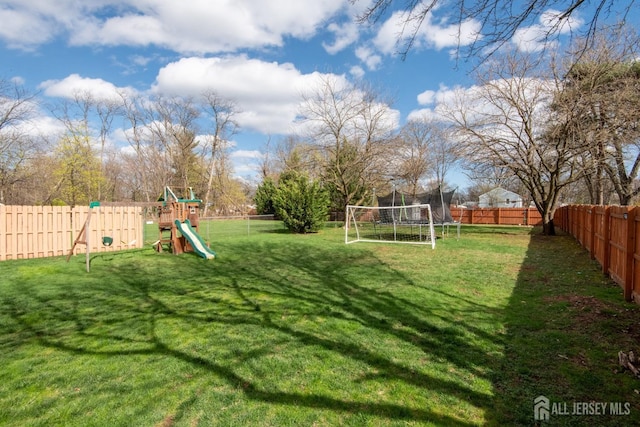 view of yard featuring a trampoline, a fenced backyard, and a playground