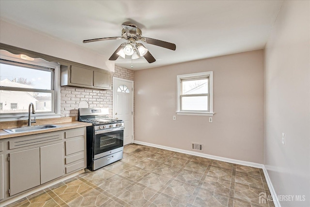 kitchen with stainless steel gas stove, sink, gray cabinetry, and ceiling fan