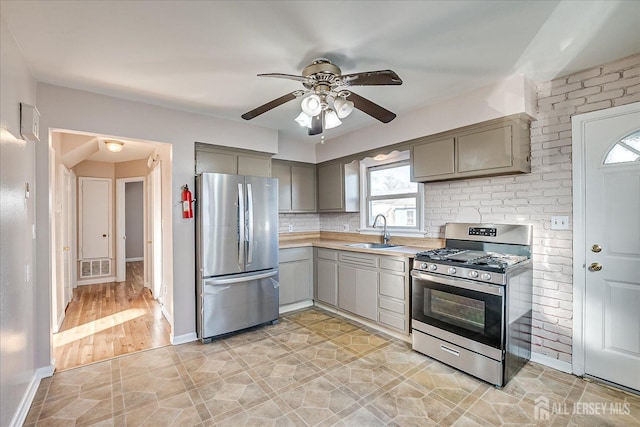 kitchen with sink, appliances with stainless steel finishes, gray cabinets, ceiling fan, and backsplash